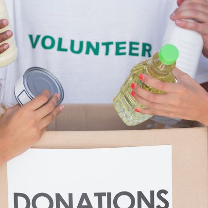 Group of volunteers putting food in donation box Business insurance