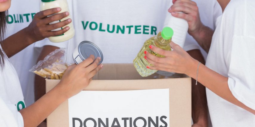 Group of volunteers putting food in donation box Business insurance