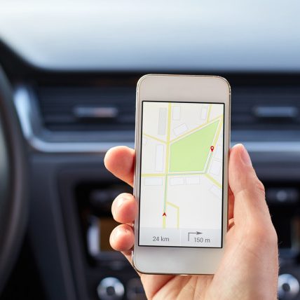 Male driver sitting in the car and holding white mobile phone with map gps navigation Auto insurance